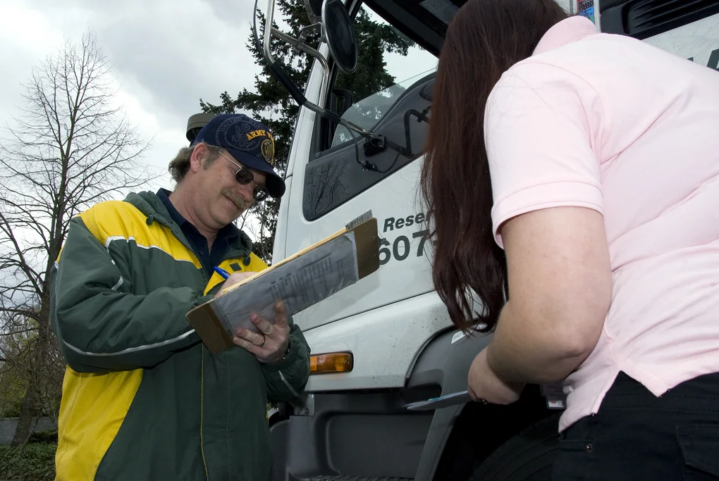 A DMV representative and a driver reviewing a pre-trip inspection checklist beside a commercial vehicle, in an archival Oregon DOT photograph.